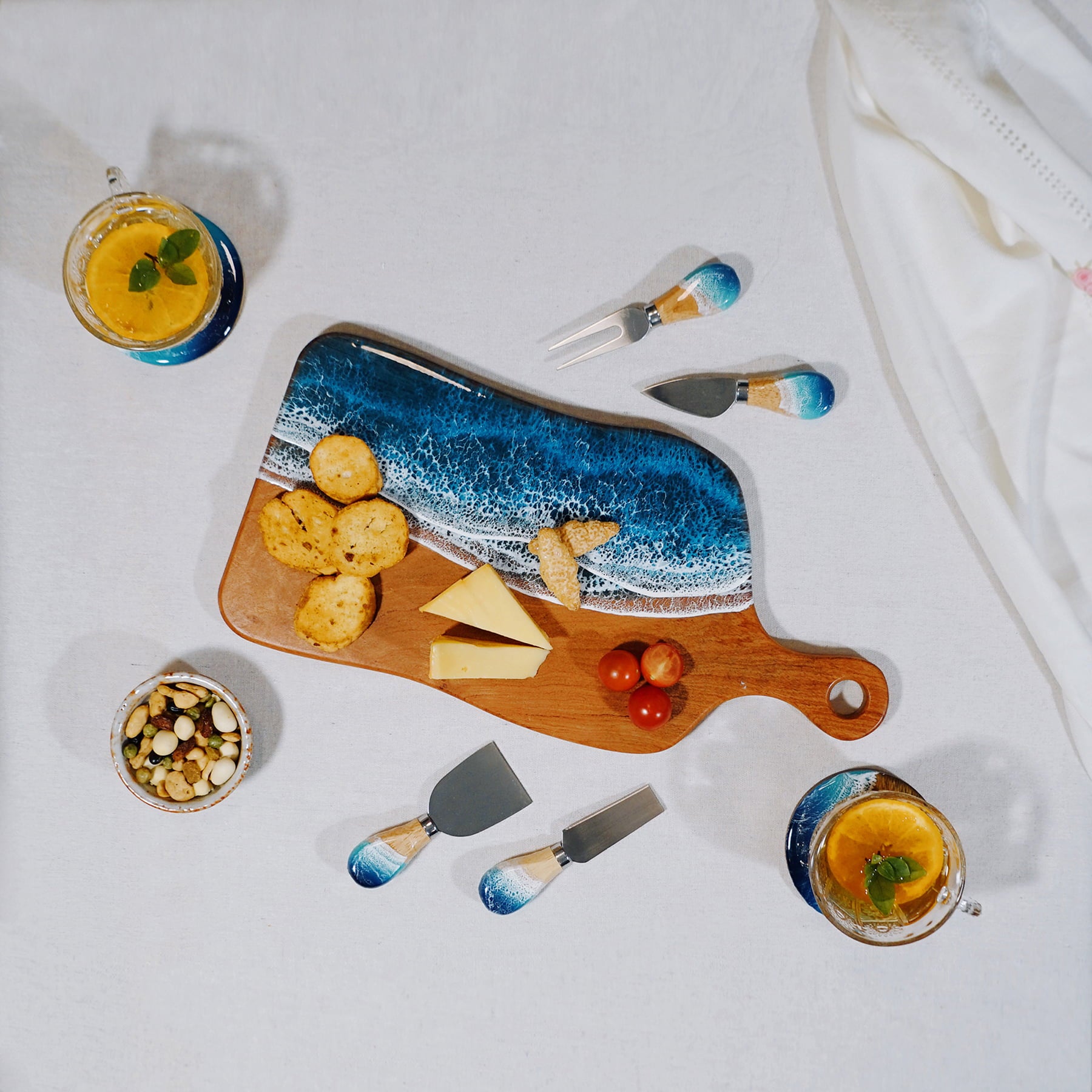 Wooden charcuterie board with ocean design, cheese, crackers, and fruit on a white surface.