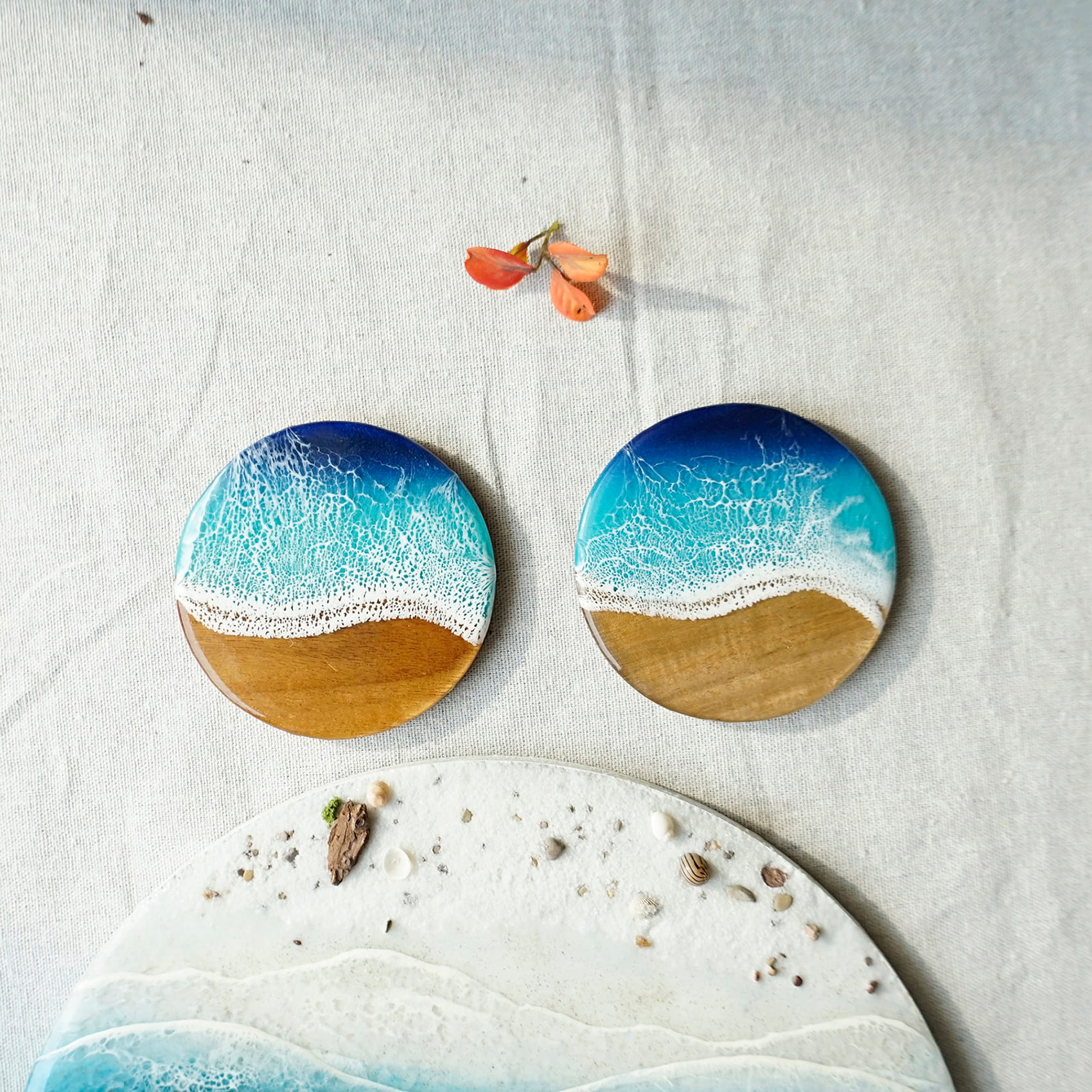Two wooden coasters with beach design on a textured surface