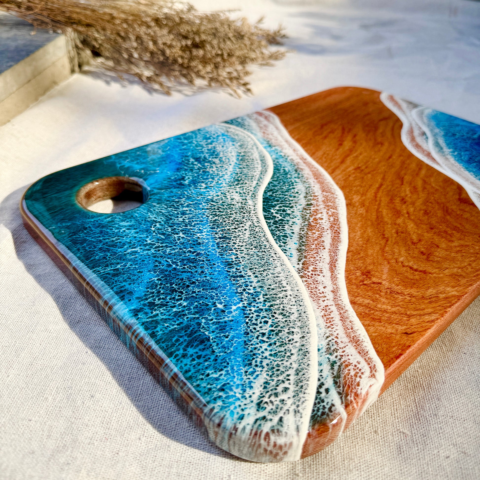 Wooden cutting board with blue resin design on a light background