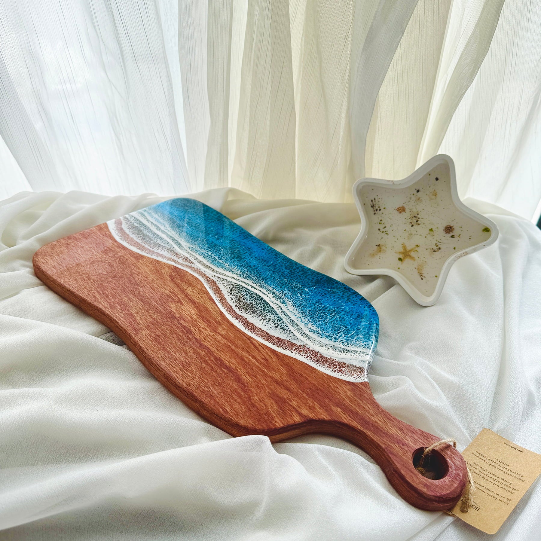 Wooden cutting board with ocean wave design and star-shaped dish on a white fabric background