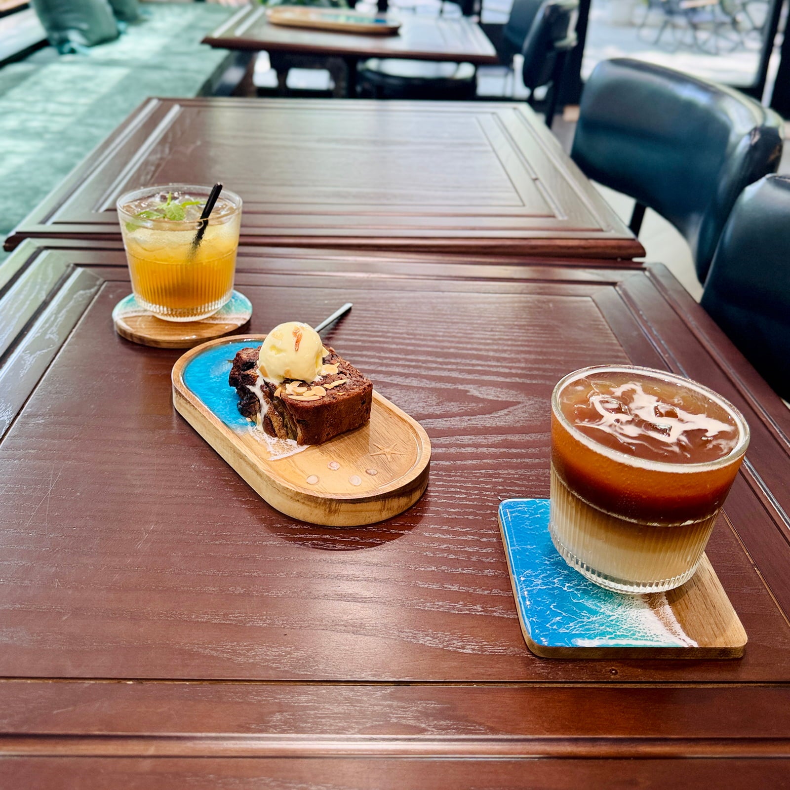 Two drinks and a dessert on a wooden table outdoors